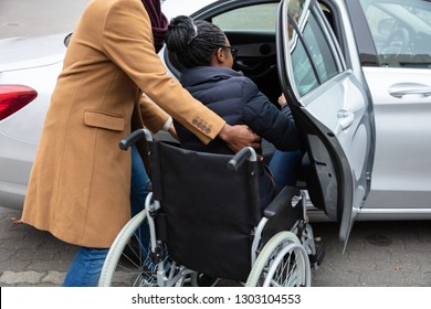 Man With Her Wife Woman Sitting On Wheelchair Moving Towards Car