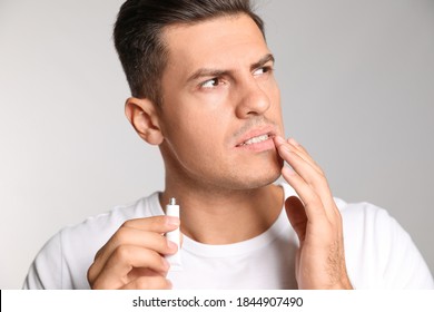 Man With Herpes Applying Cream On Lips Against Light Grey Background