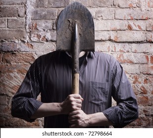 A man hides his face behind a shovel. Depersonalization, a metaphor.