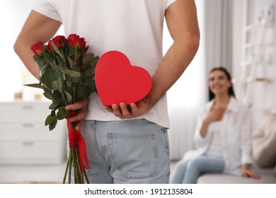 Man hiding beautiful bouquet and gift box behind his back at home, closeup. Valentine's day celebration - Powered by Shutterstock