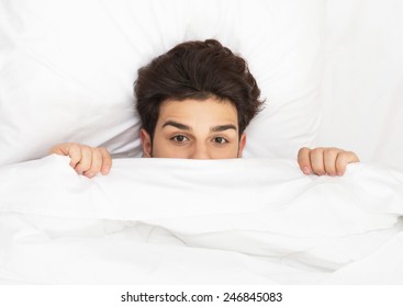 Man hiding in bed under the sheets