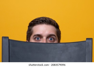 Man Hiding Behind A Chair With Suprised Look