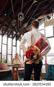 Man Hiding Box Of Chocolate And Bouquet Of Flowers For Girlfriend Behind His Back