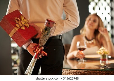 Man Hiding Red Rose And Gift For His Girlfriend Behind His Back