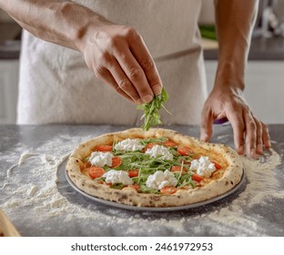 A man from a high angle view is placing arugula on baked pizza dough. - Powered by Shutterstock