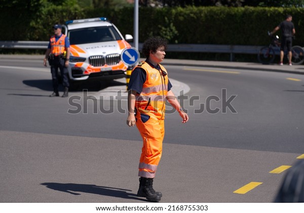 Man in high visibility
clothes managing traffic at first stage of bicycle race Tour de
Suisse on a sunny summer day. Photo taken June 12th, 2022, Forch,
Switzerland.