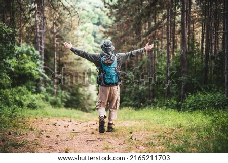 Similar – Hiker woman with backpack raising her arms into the forest