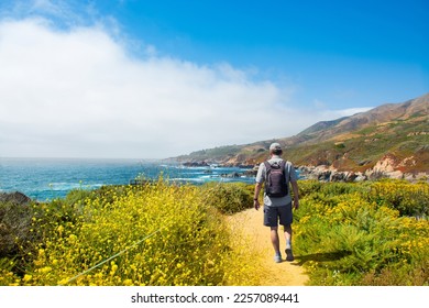 Man hiker enjoying walk by the ocean.  Man hiking alone on vacation. Summer mountain coastal landscape. View from highway 1. Garrapata State Park, Big Sur, California, USA. - Powered by Shutterstock