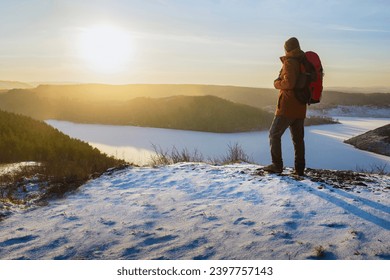 Man hiker hiking in winter. Traveler hiking in winter and enjoying mountains landscape at sunset. Freedom healthy lifestyle concept. - Powered by Shutterstock