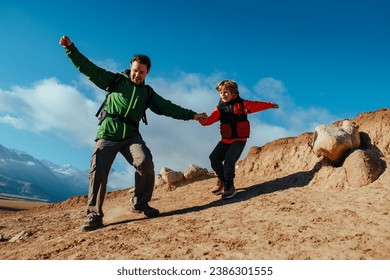 Man hiker and his son climbing down from rock