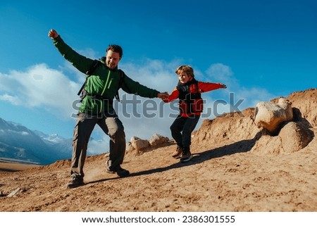 Man hiker and his son climbing down from rock