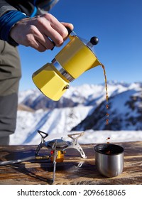 Man Hiker Pouring Coffee From Yellow Moka Mocha Pot Outdoors In The Snow Winter Mountains. Old Style Coffee Vintage Pot Outdoor Camping