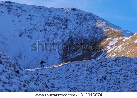 Man hiker reaching the top of majestic and wild mountains. Snowy autumn weather with blue sky. High Tatras national park, Slovakia. Western Tatras. 