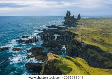 Man hiker in yellow jacket stand on the peak of the rock in outdoor park in Iceland. Londrangar