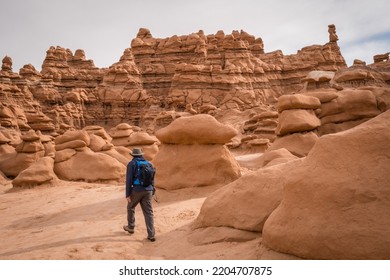 Man Hiking Among Red Rock Formations In Goblin Valley State Park In Utah.