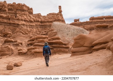 Man Hiking Among Red Rock Formations In Goblin Valley State Park In Utah.