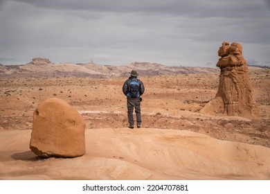 Man Hiking Among Red Rock Formations In Goblin Valley State Park In Utah.