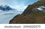 Man hiking Antarctic mountains green rock hill. Frozen ocean, ice snow covered island in background. Landscape of polar winter nature. Antarctica travel exploration. Tourism expedition to South pole