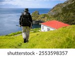 Man hiking Cape Brett Track. Cape Brett Hut in the distance. Bay of Islands. New Zealand.