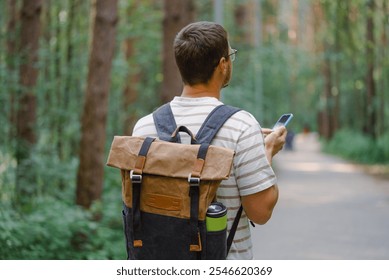 Man hiking in a lush forest, using his smartphone for navigation - Powered by Shutterstock