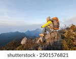 A man is hiking in the mountains with a backpack. He is hiking in the mountains in the morning while the sunlight is soft.