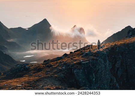 Man sitting on a cliff of a fjord with low sun on the European Arctic Ocean