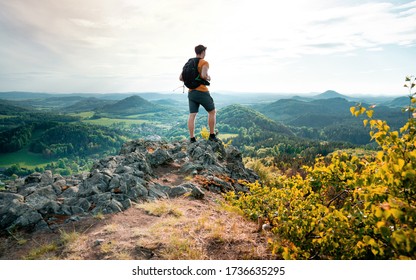 Man hiking on top of a rocky mountain peak. Steep cliff, rocky part of path with view into distance. Scenic landscape of Lunation Mountains, Czech Republic 