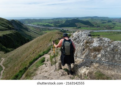 Man Hiking Te Mata Peak Track, Holding Chain To Descent Steep Downhill, Views Of Hawke’s Bay. 