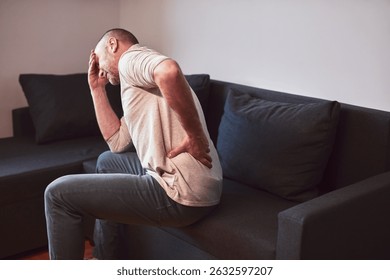 Man with hip, back and sciatica pain at home.