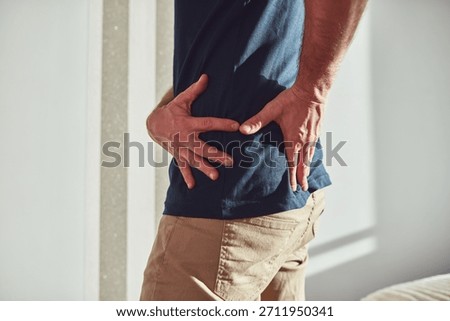 Man with hip, back, spine and sciatica pain at home.