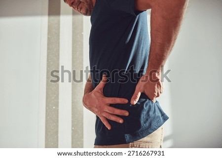 Man with hip, back, spine and sciatica pain at home.