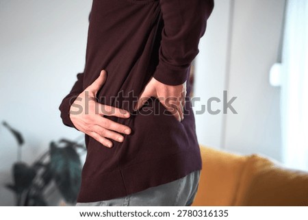 Man with hip, back, spine and sciatica pain at home.