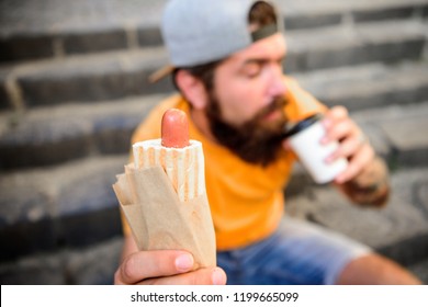 Man Hipster Have Quick Lunch Sit Stairs Background. He Likes Urban Lunch. Delicious Snack. Coffee To Go And Street Food Choice Of Youth. Paper Cup Coffee And Hot Dog Street Food Traditional Snack.