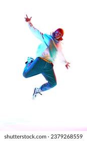 Man in his 30s wearing sport style clothes and dancing breakdance isolated over white studio background in neon light. Concept of contemporary dance, street style, fashion, hobby, youth. Ad