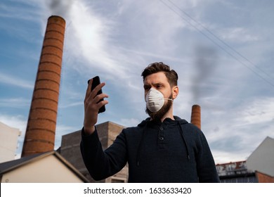 Man with his anti pollution mask on checking air quality , smoke from factory in the back 