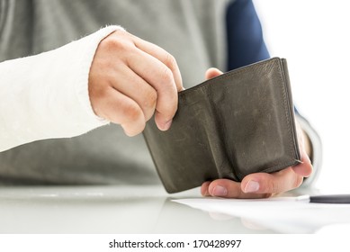 Man With His Arm In A Plaster Cast Holding A Wallet Removing Money Conceptual Of The Cost And Expense Of Emergency Medical Treatment At A Hospital Or Doctor