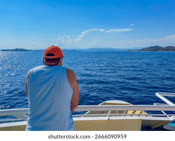 Man with his back to the camera standing on a ship deck looking at the sea and the horizon Athos Greece, concept of travel agency, vacation planning, cruise company