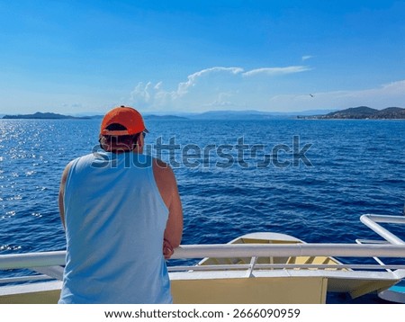 Man with his back to the camera standing on a ship deck looking at the sea and the horizon Athos Greece, concept of travel agency, vacation planning, cruise company