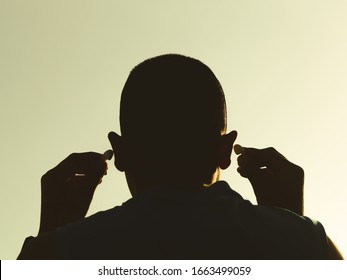 A man with his back turned to headphones The hand is holding the bluetooth earphone on both sides With a sky background