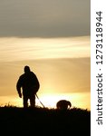 Man with his best friend dog walking in the sunset on Chiliwack field