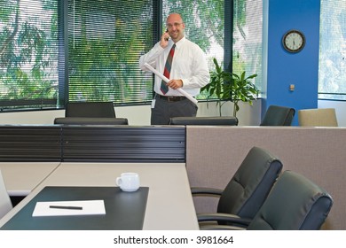 A Man In His Corporate Office Environment, On The Phone And At Work