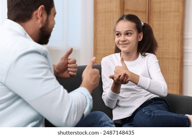 Man and his daughter using sign language for communication at home - Powered by Shutterstock