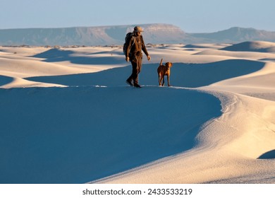 Man and his dog walking on white sand dunes in White Sands. Alamogordo. New Mexico. USA - Powered by Shutterstock