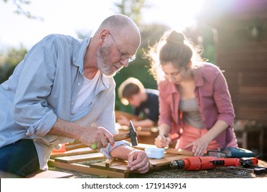 A Man And His Family Are Building Wooden Planters For Their Vegetable Garden