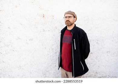 man in his forties in front of fat white stucco wall, man with backwards beret and maroon T-shirt. Incipient barrel. - Shutterstock ID 2288553519