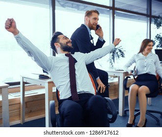 A Man With His Hands Up Is Having Fun In An Office Chair. Relaxed Working Environment After Meeting