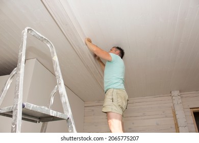 A Man In His House Installs A Wooden Plinth On The Ceiling