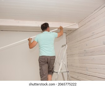 A Man In His House Installs A Wooden Plinth On The Ceiling