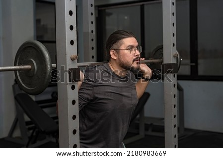 A man in his late 30s makes a comeback at the gym. Doing back squats with a relatively light weight. A dad getting back in shape.