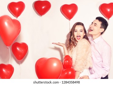 Man With His Lovely Sweetheart Girl Dance And Have Fun At Lover's Valentine Day. Valentine Couple Party. Background Red Balloons Hearts. Love Concept. Crazy. Empty Copy Space For Your Text.